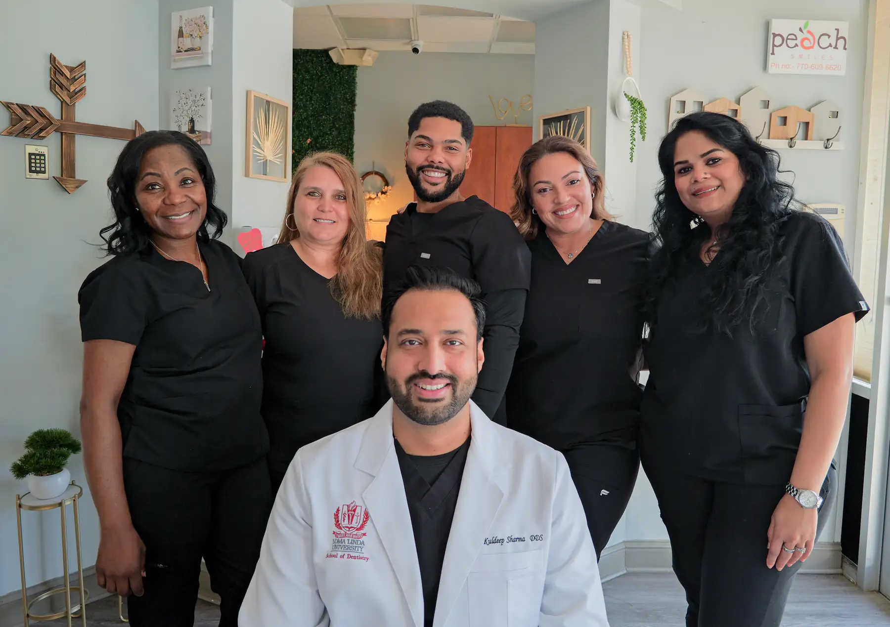 The Peach Smiles dental team gathered in the office, with the dentist seated in front